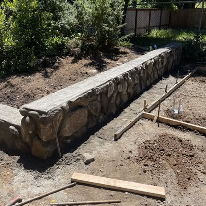 Stone retaining wall along a landscaped backyard